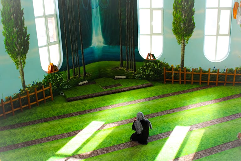 A person prays in a beautifully designed indoor space with nature-themed decor.